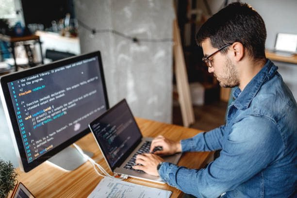 A man using a laptop and a monitor while doing programming works