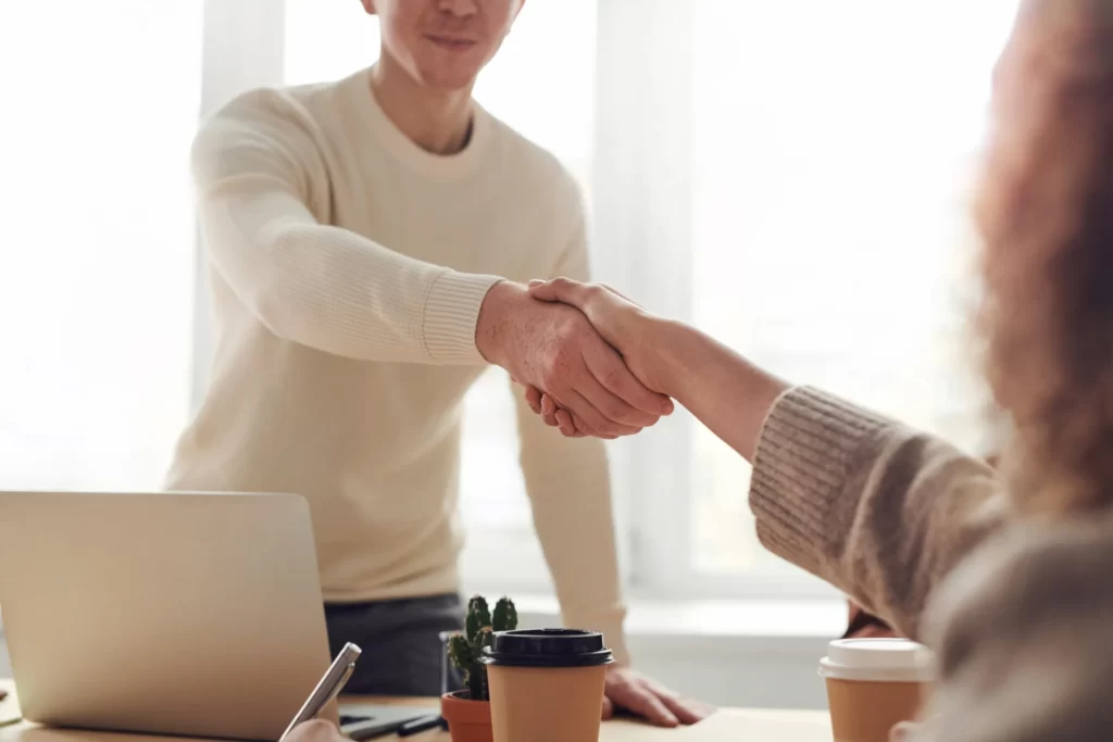 Man and woman shaking hands at office desk